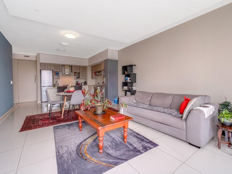 An open-plan living and kitchen area featuring tiled flooring, modern cabinetry, and a functional layout suitable for contemporary apartment living.