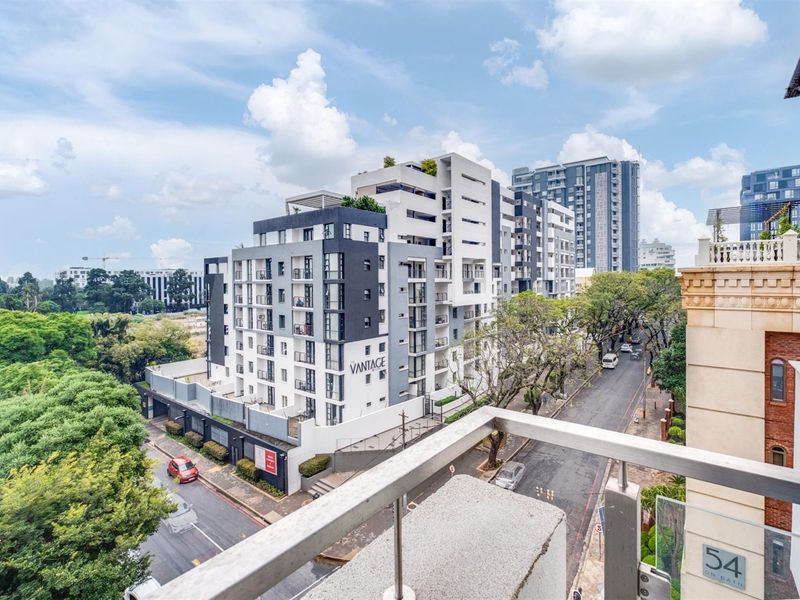 Elevated view from a balcony overlooking the surrounding urban landscape and modern apartment complex.