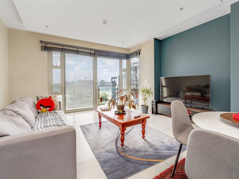 Bright open-plan living area featuring large floor-to-ceiling sliding glass doors that open onto a private balcony with expansive views.