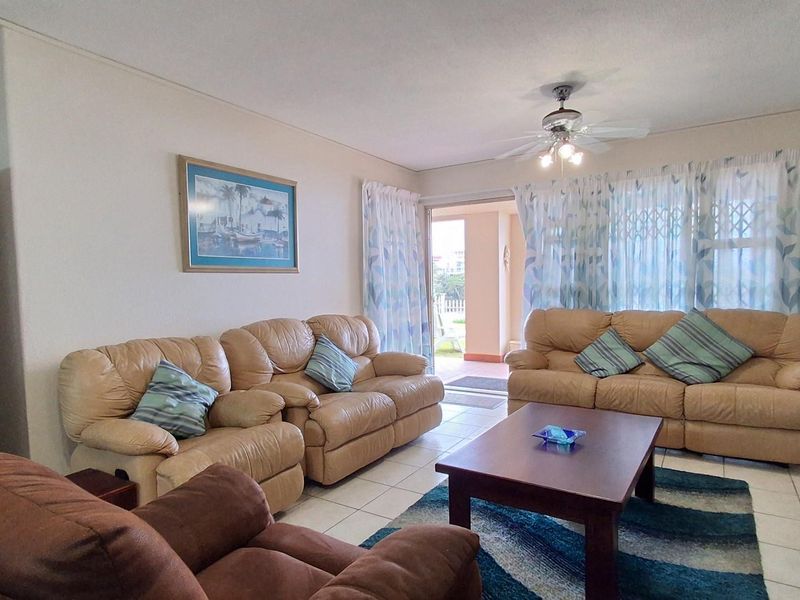 Spacious living room featuring tiled flooring, a ceiling fan, and sliding glass doors providing direct access to an outdoor patio area.
