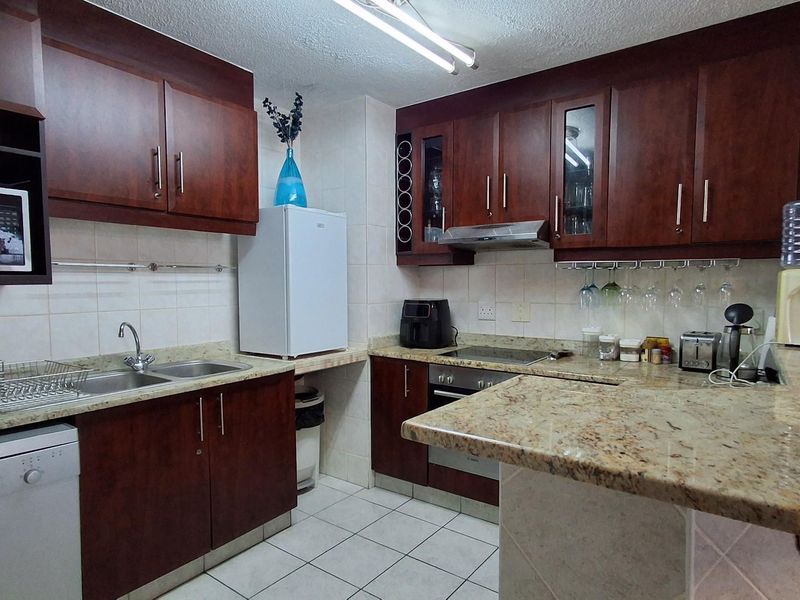 A functional kitchen featuring dark wood cabinetry, granite countertops, a breakfast bar, and integrated stainless steel appliances.