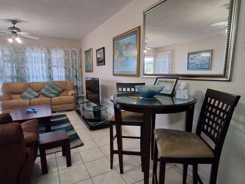 Open plan living and dining area featuring tiled flooring, a ceiling fan, and sliding glass doors leading to an outdoor balcony.