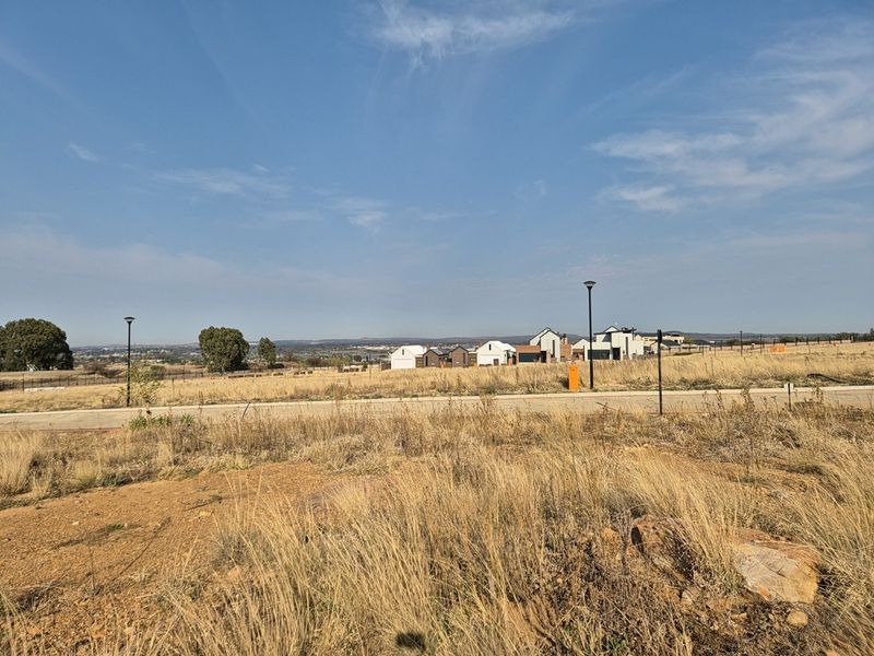 A wide-angle view of the vacant residential land, featuring established street infrastructure, perimeter fencing, and surrounding estate development.