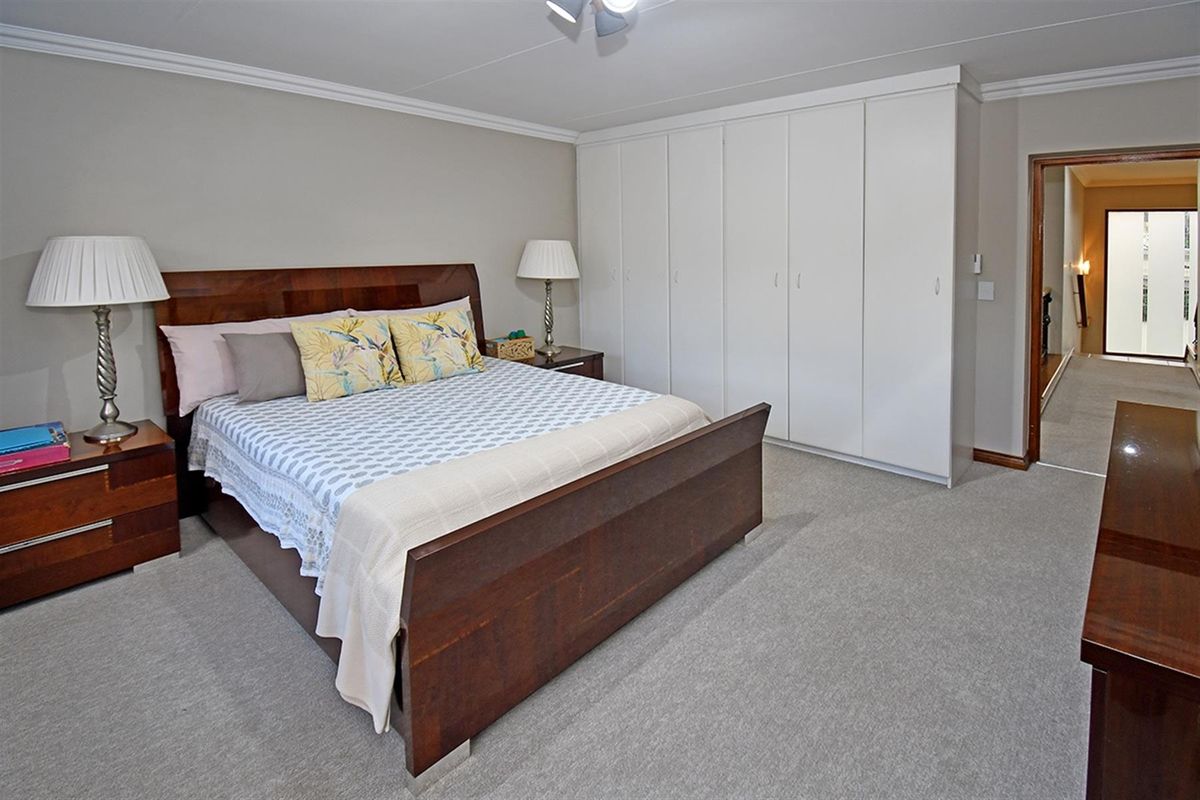 Spacious bedroom featuring neutral carpeting, crown molding, and extensive built-in floor-to-ceiling white cabinetry for ample storage.