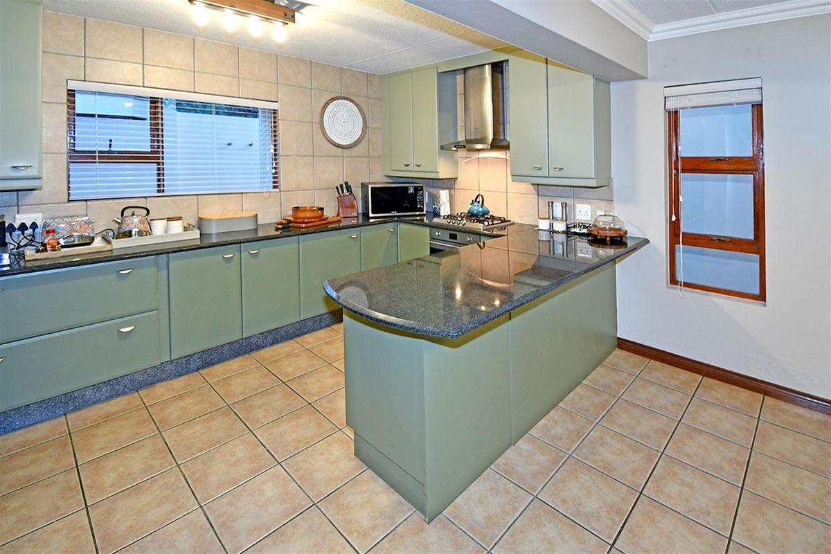 Functional kitchen featuring sage green cabinetry, granite countertops, tiled backsplash, built-in oven, gas hob, and stainless steel extractor fan.