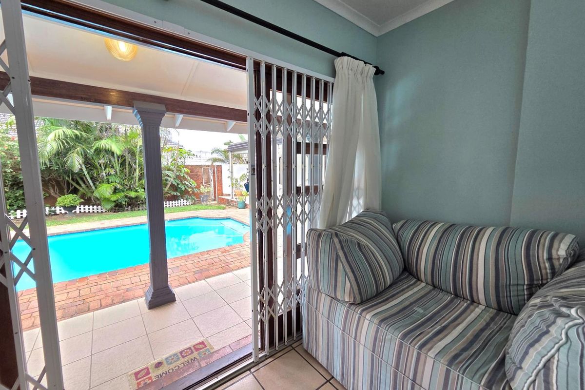Living area featuring sliding security doors opening onto a covered patio and swimming pool area.