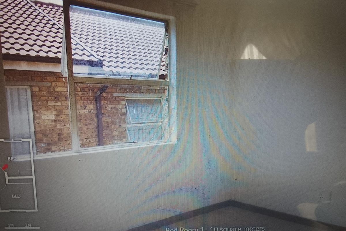 An empty bedroom featuring a metal-framed window with visible damage, requiring maintenance and cosmetic updates.