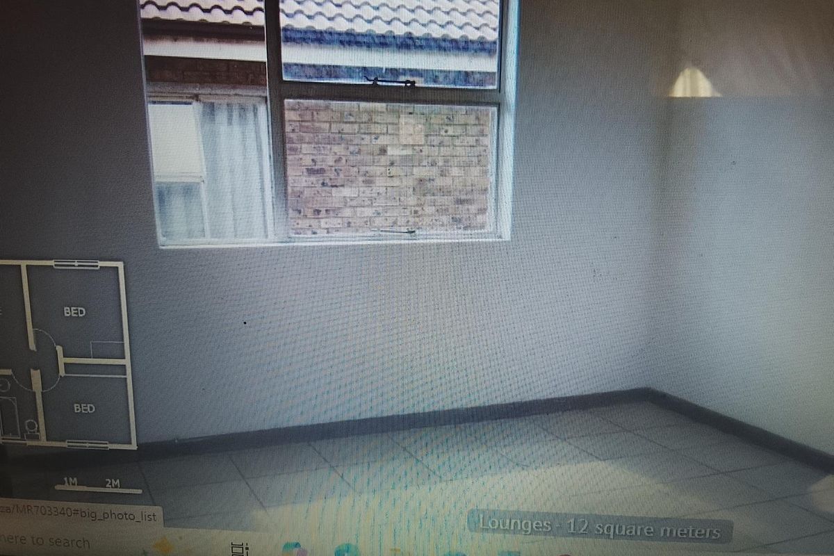 An empty living room featuring tiled flooring and a window with an aluminium frame.
