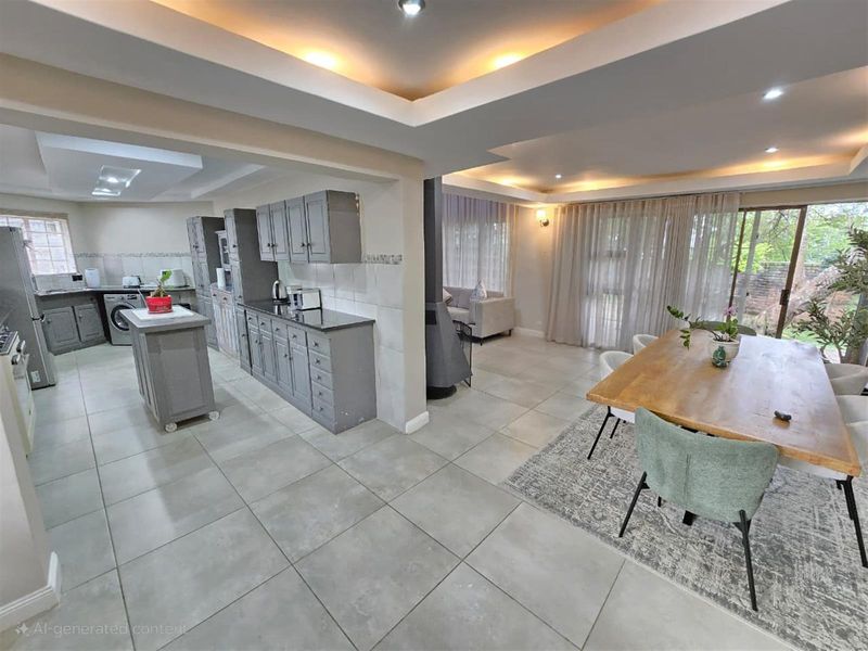 Spacious open-plan kitchen and dining area featuring modern grey cabinetry, granite countertops, tiled flooring, and a built-in fireplace, creating a seamless living space.