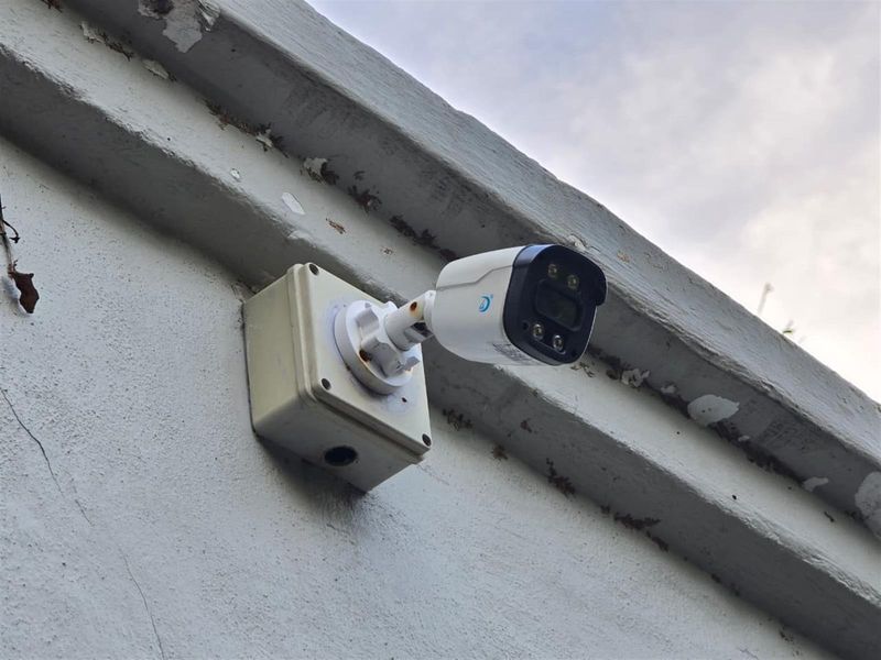 Close-up view of a wall-mounted security camera installed on the exterior facade of the property.