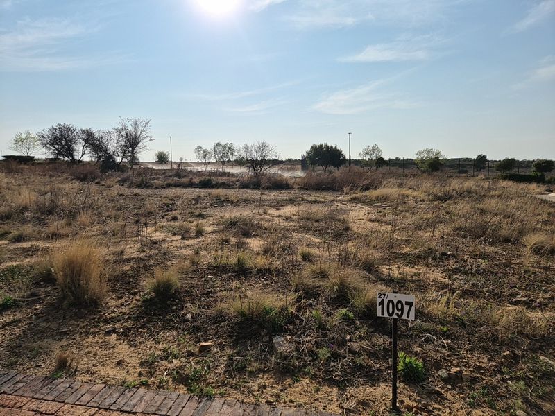 A vacant residential plot of land featuring natural vegetation and a clear boundary marker, ready for development.