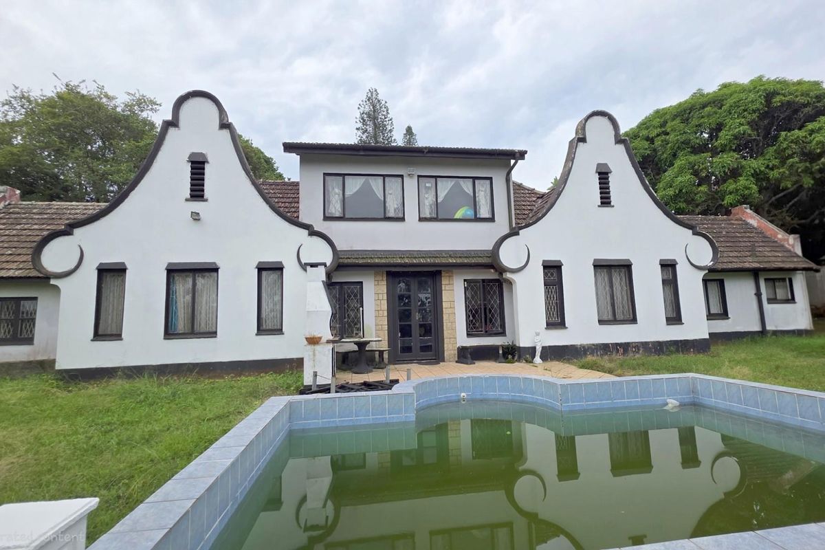 Rear view of a Cape Dutch style house featuring a swimming pool, tiled patio area, and traditional gabled architecture.