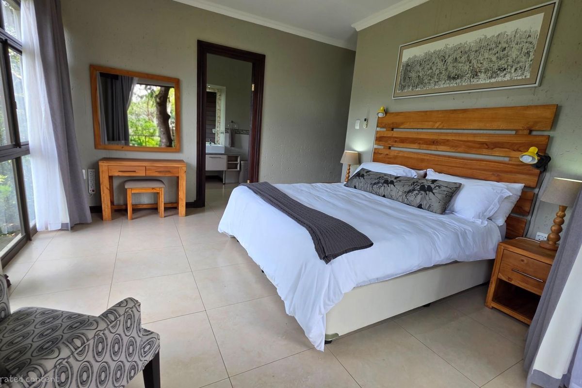 A spacious bedroom featuring large windows, tiled flooring, and an en-suite bathroom entrance, offering a bright and comfortable living space.