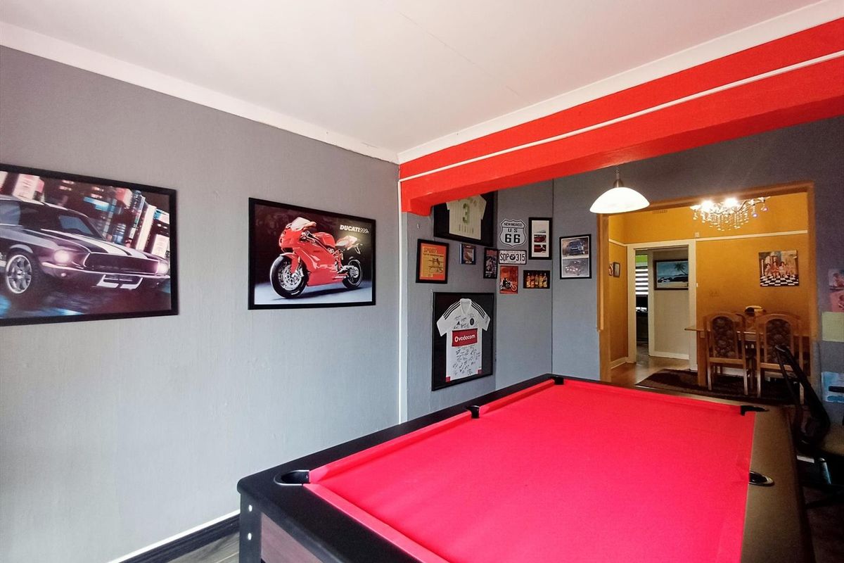 A living area featuring grey walls, a red accent beam, and coving, with an open transition into an adjacent dining space.