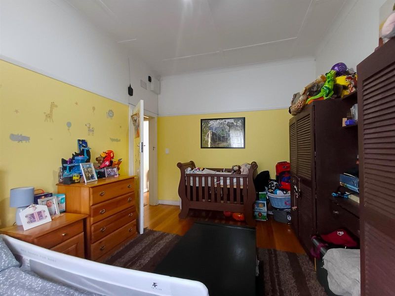 A bedroom featuring hardwood flooring and a classic picture rail, currently utilized as a nursery.