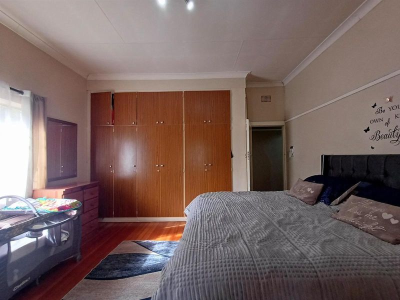 A spacious bedroom featuring warm hardwood flooring and extensive built-in wooden cupboards, offering ample storage space and a classic aesthetic.
