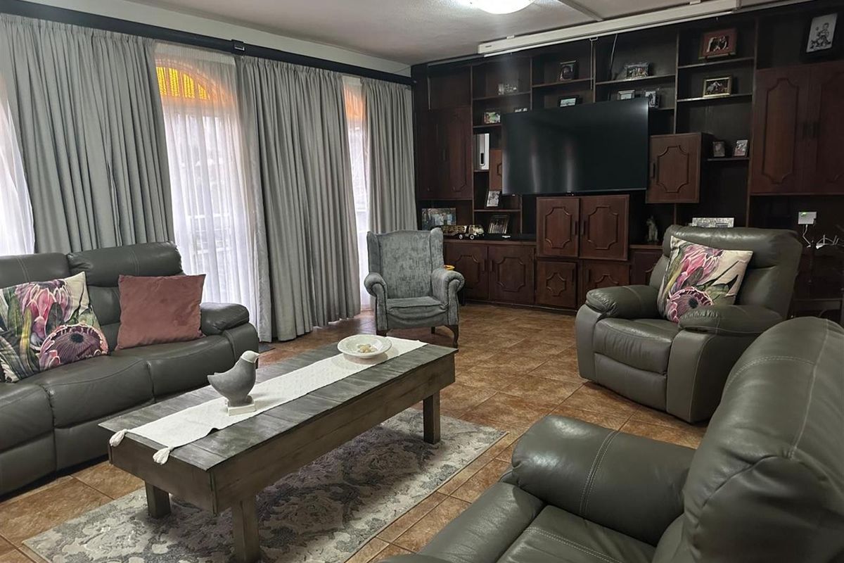 A spacious living room featuring extensive built-in wooden cabinetry and tiled flooring, offering a functional layout with ample storage space.