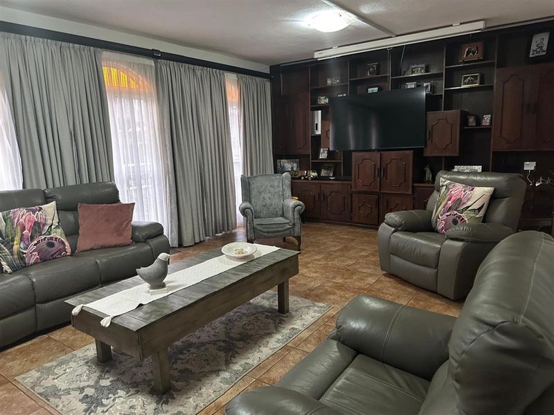 A spacious living room featuring extensive built-in wooden cabinetry and tiled flooring, offering a functional layout with ample storage space.