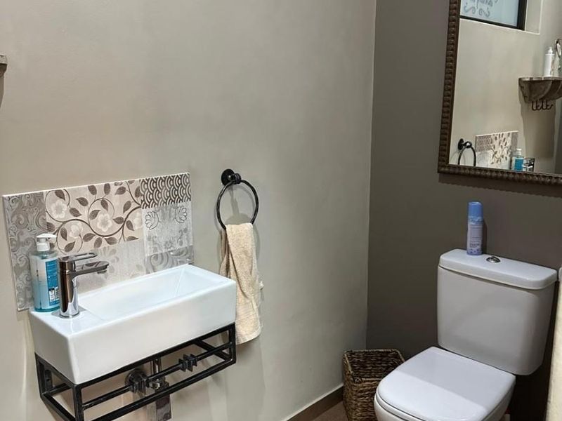 A compact guest bathroom featuring a modern wall-mounted basin with decorative tile backsplash and a standard toilet.