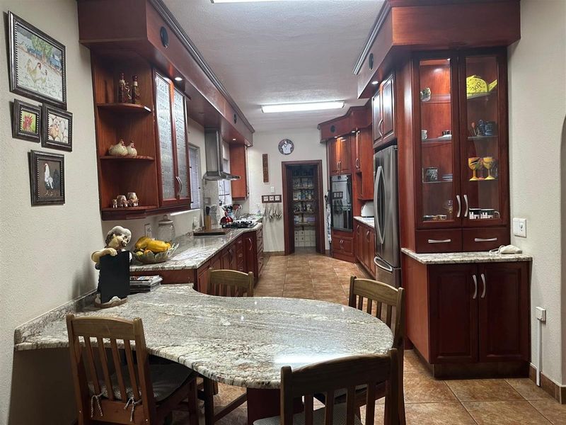 Spacious kitchen featuring extensive cherry wood cabinetry, granite countertops, a built-in oven, gas cooktop, and a convenient walk-in pantry.