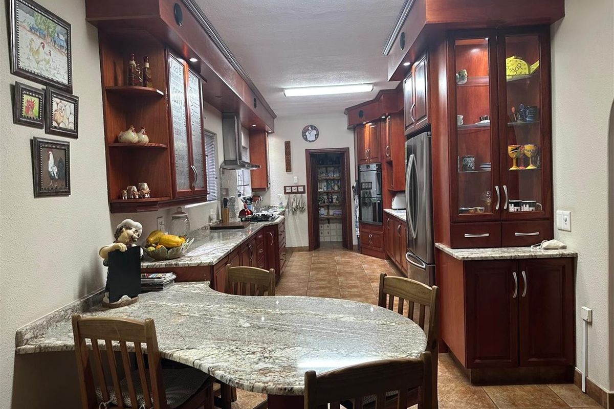 Spacious kitchen featuring extensive cherry wood cabinetry, granite countertops, a built-in oven, gas cooktop, and a convenient walk-in pantry.