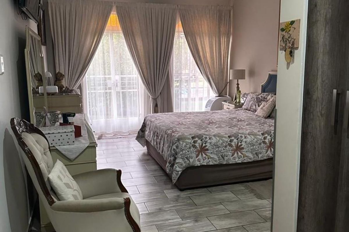 A well-maintained bedroom featuring modern wood-look tiled flooring, a ceiling fan, and a built-in wardrobe with access to a private outdoor area.