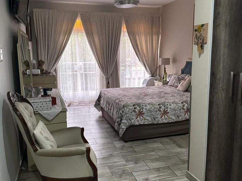 A well-maintained bedroom featuring modern wood-look tiled flooring, a ceiling fan, and a built-in wardrobe with access to a private outdoor area.