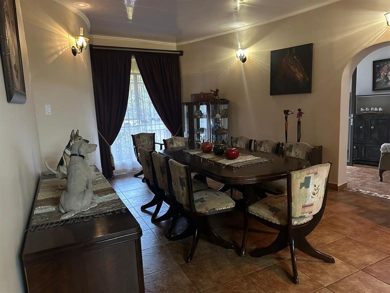 A traditional dining room featuring tiled flooring, an arched entryway, and wall-mounted lighting, providing a functional space for family meals and entertaining.