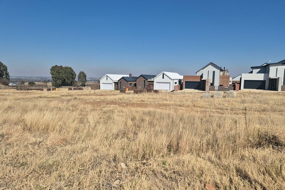 A view of a vacant residential plot with surrounding modern housing developments in the background.