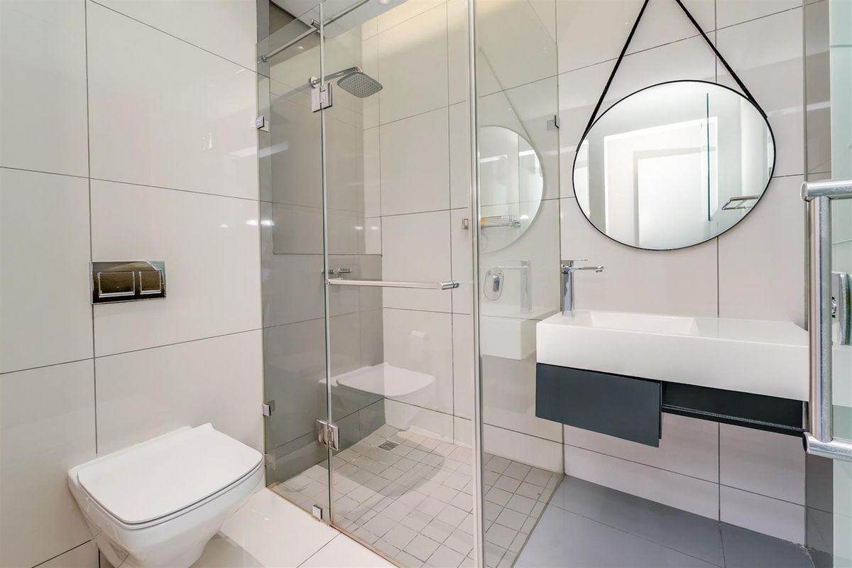 Modern bathroom featuring a glass-enclosed walk-in shower, wall-mounted toilet, and a sleek floating vanity with a contemporary basin.