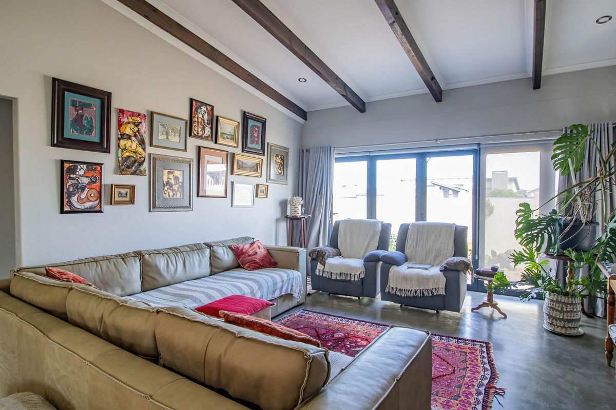 Spacious living room featuring exposed timber ceiling beams, polished concrete flooring, and large sliding glass doors providing ample natural light and outdoor access.