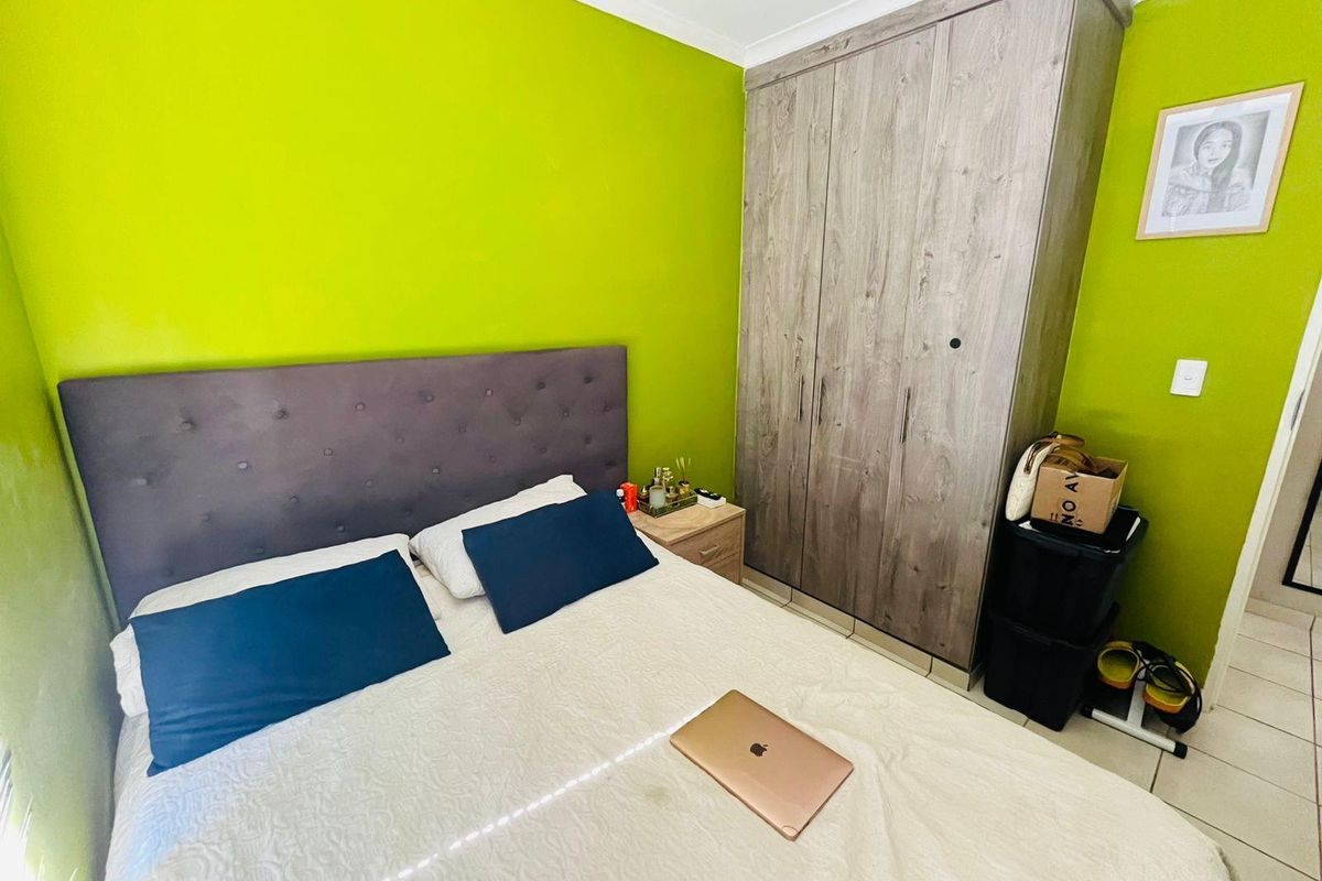 A bedroom featuring a built-in wooden wardrobe and tiled flooring, finished with bright green wall paint.