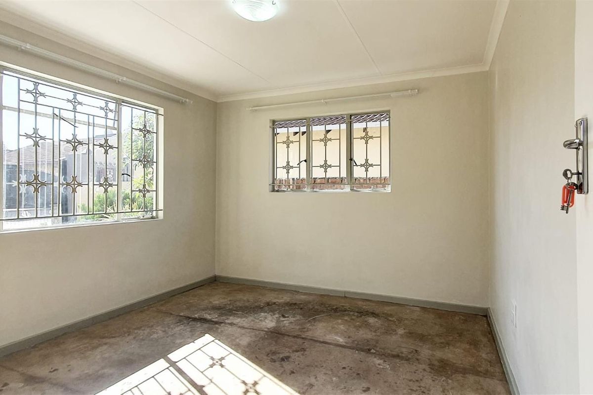 A vacant bedroom featuring security bars on the windows and unfinished concrete flooring, offering a blank canvas for renovation.
