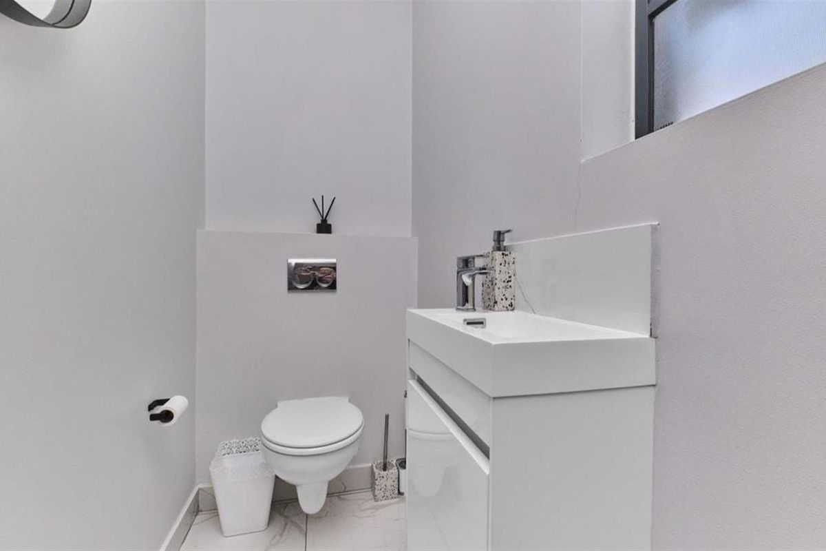 Modern guest bathroom featuring a wall-hung toilet with concealed cistern and a sleek vanity basin with chrome fixtures.