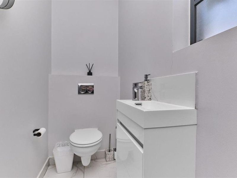 Modern guest bathroom featuring a wall-hung toilet with concealed cistern and a sleek vanity basin with chrome fixtures.