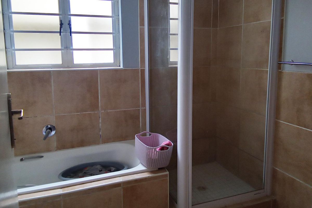 A functional bathroom featuring a built-in bathtub, a separate shower enclosure, and tiled wall finishes.