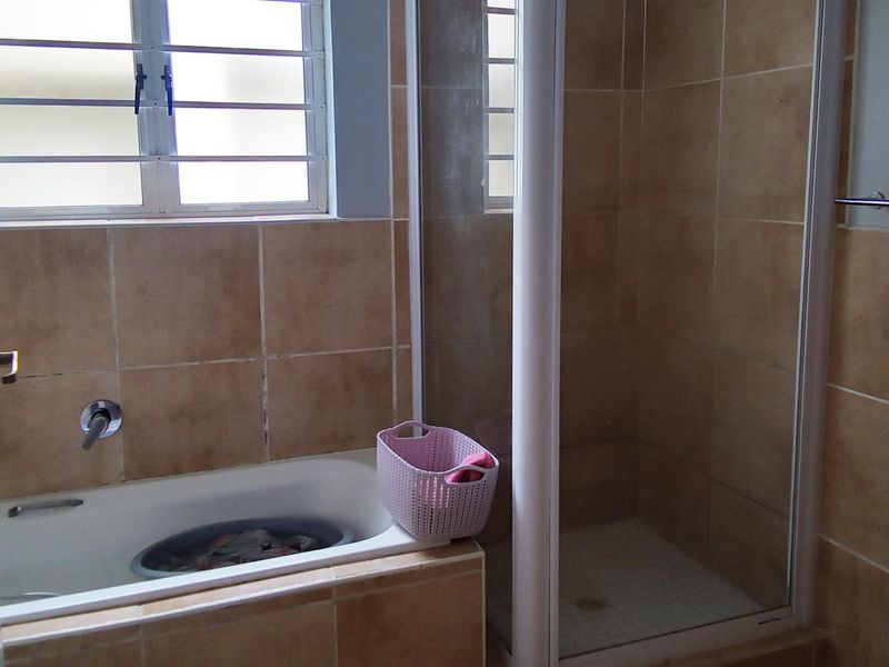 A functional bathroom featuring a built-in bathtub, a separate shower enclosure, and tiled wall finishes.
