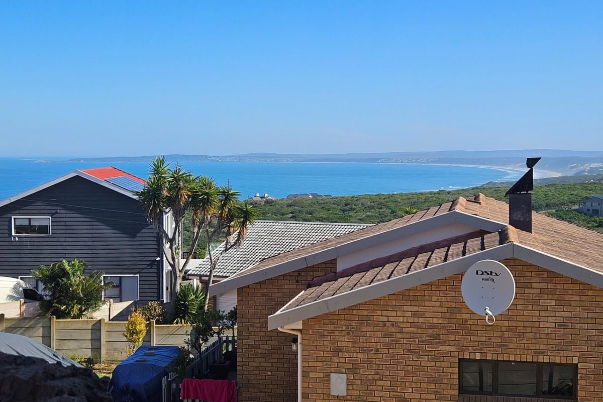 Elevated coastal view overlooking the ocean and surrounding residential neighborhood, featuring brick and timber-clad exterior structures.