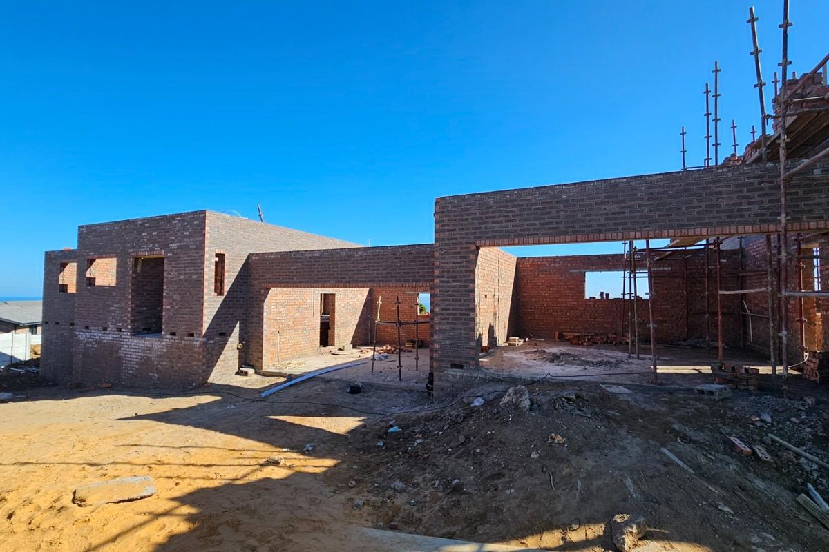 A view of a residential property currently under construction, featuring exposed brick walls and scaffolding on a cleared building site.