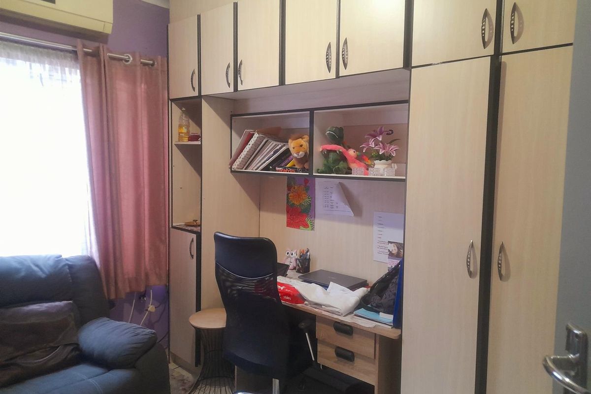A bedroom featuring built-in cabinetry with integrated desk space and overhead storage units, providing functional storage and workspace solutions.