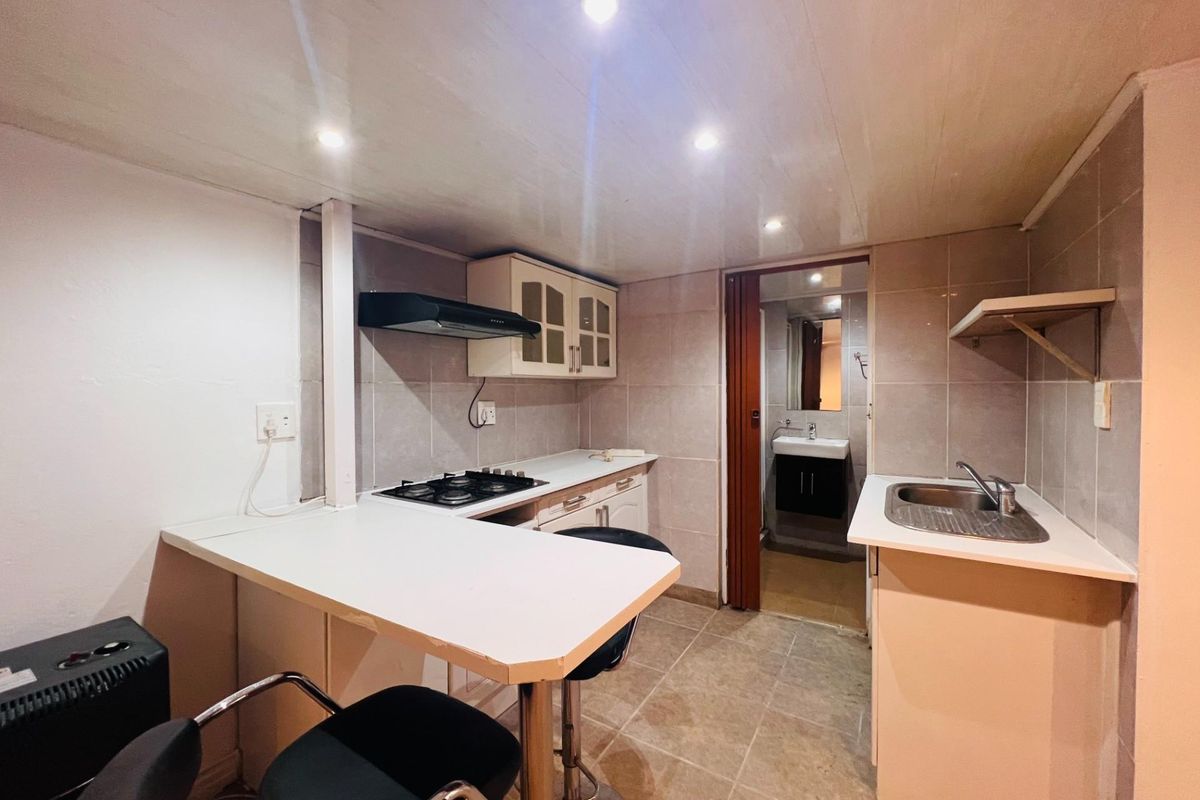 Compact kitchen featuring built-in cabinetry, gas hob, extractor fan, and a breakfast counter, with direct access to an adjoining bathroom.