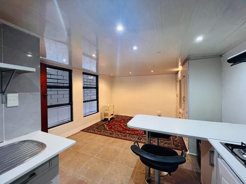 Open-plan kitchen and living area featuring tiled floors, built-in cabinetry, a hob, and recessed lighting, offering a functional and versatile living space.