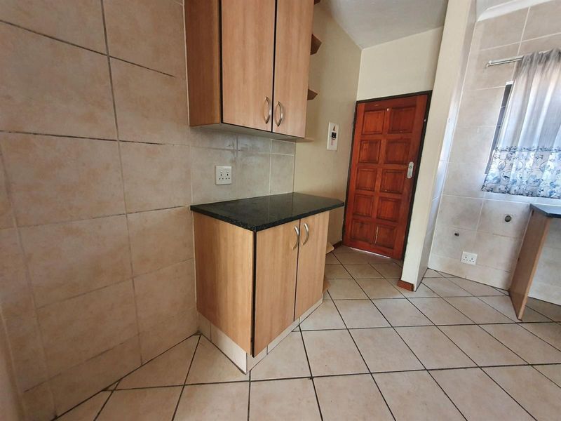 A functional kitchen area featuring laminate cabinetry, granite countertops, and neutral ceramic tiling throughout.