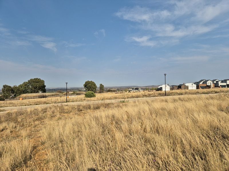 A wide-angle view of the vacant residential land, featuring established street infrastructure, surrounding neighborhood development, and open landscape vistas.