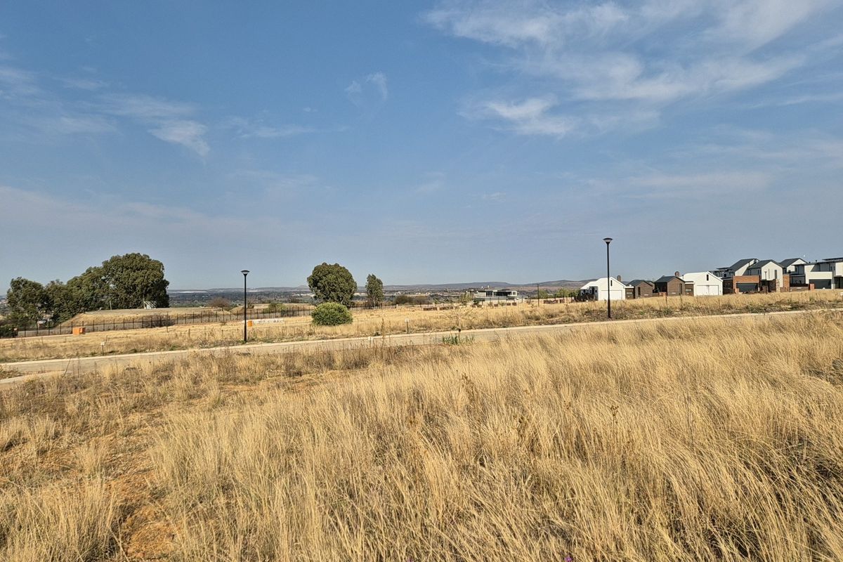 A wide-angle view of the vacant residential land, featuring established street infrastructure, surrounding neighborhood development, and open landscape vistas.