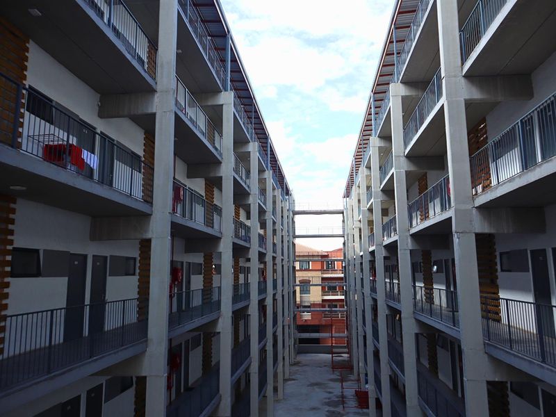 A view of the central courtyard and exterior walkways between two multi-story apartment blocks, featuring concrete construction and metal safety railings.