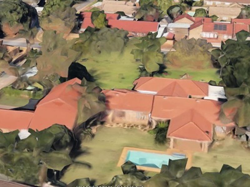 An aerial view of the property showing the house layout, tiled roof, swimming pool, and surrounding garden area.