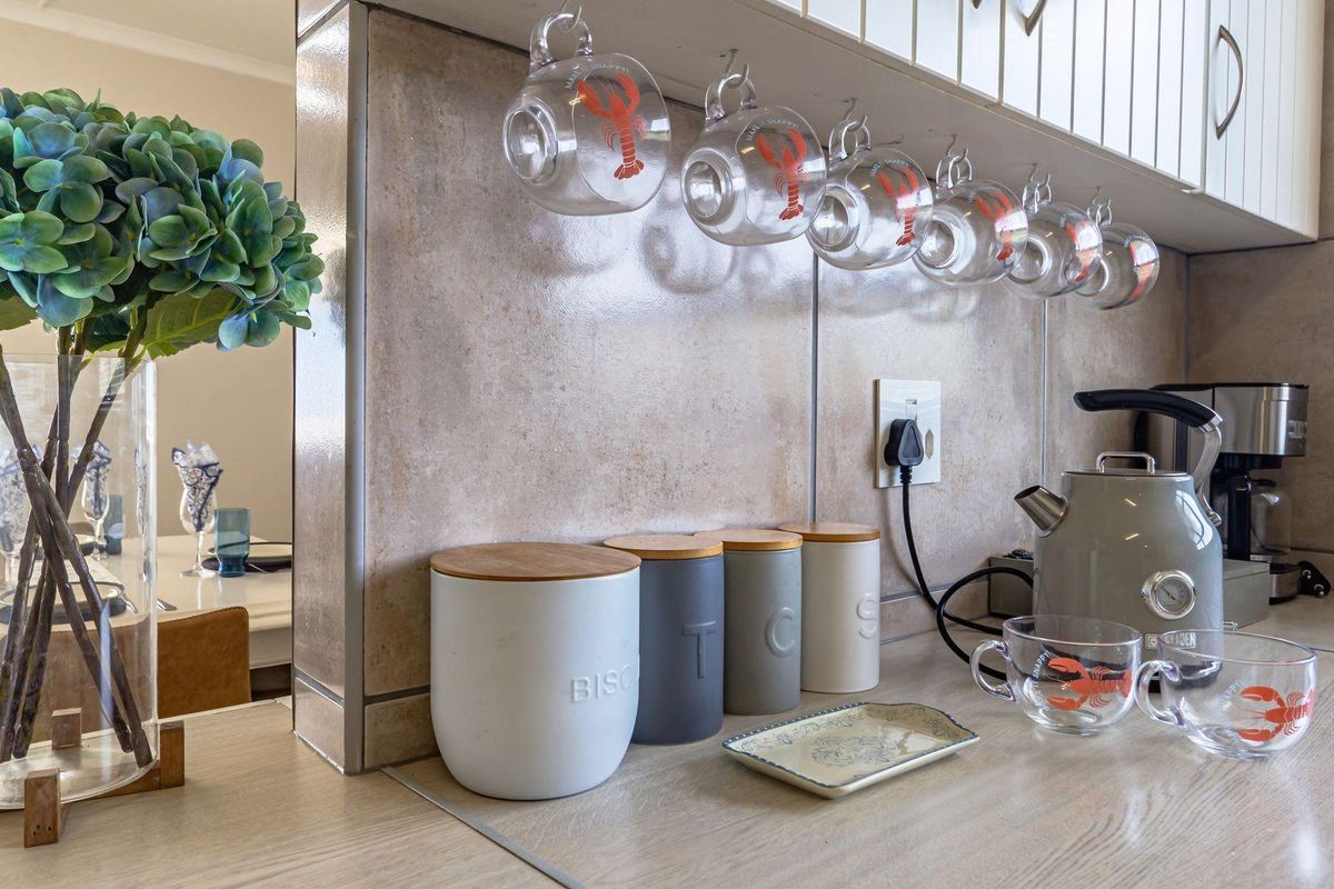 A close-up view of a kitchen counter featuring tiled splashbacks, overhead cabinetry, and integrated electrical outlets.