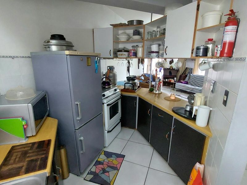 Compact kitchen featuring built-in cabinetry, tiled splashbacks, and a functional layout with integrated appliance space.