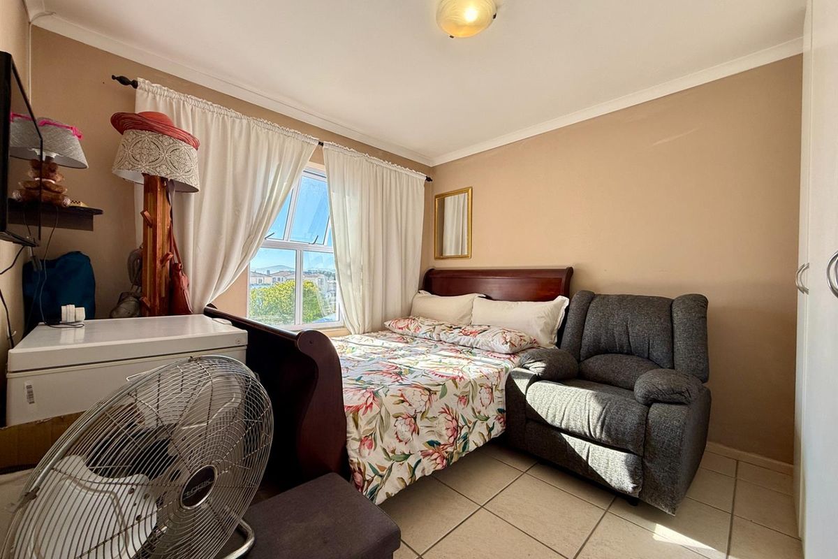 A compact bedroom featuring tiled flooring, a window with natural light, and built-in cupboard space.